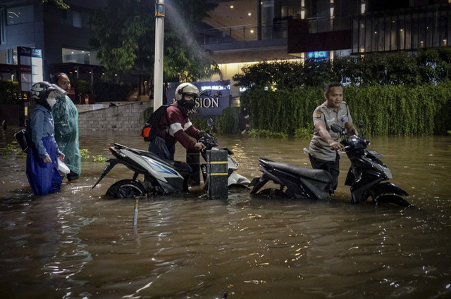 Petugas keamanan membantu mendorong sepeda motor warga saat banir malanda kawasan Kemang, Jakarta Selatan pada 6 Oktober 2022. Foto: Jamal Ramadhan/kumparan