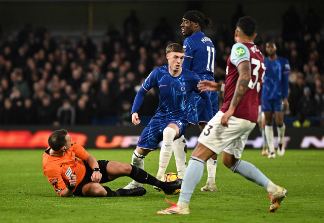 Wasit Stuart Attwell jatuh dekat Cole Palmer saat Chelsea vs West Ham dalam laga lanjutan Liga Inggris 2024/25 di Stadion Stamford Bridge, London, pada Selasa (4/2) dini hari WIB. Foto: REUTERS / Dylan Martinez