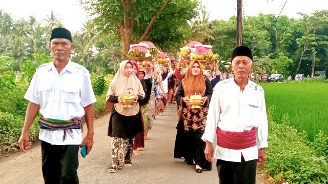 Rombongan berbaris menuju makam leluhur sembari membawa dulang. foto: L Dedy S