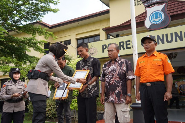 Kapolres Gunungkidul, AKBP Ary Mutini, memberikan penghargaan kepada 3 nelayan dan Koordinator SAR Linmas Wilayah II Baron, Marjono, karena sudah berkontribusi menyelamatkan 13 siswa yang terseret gelombang Pantai Drini. Foto: Polres Gunungkidul