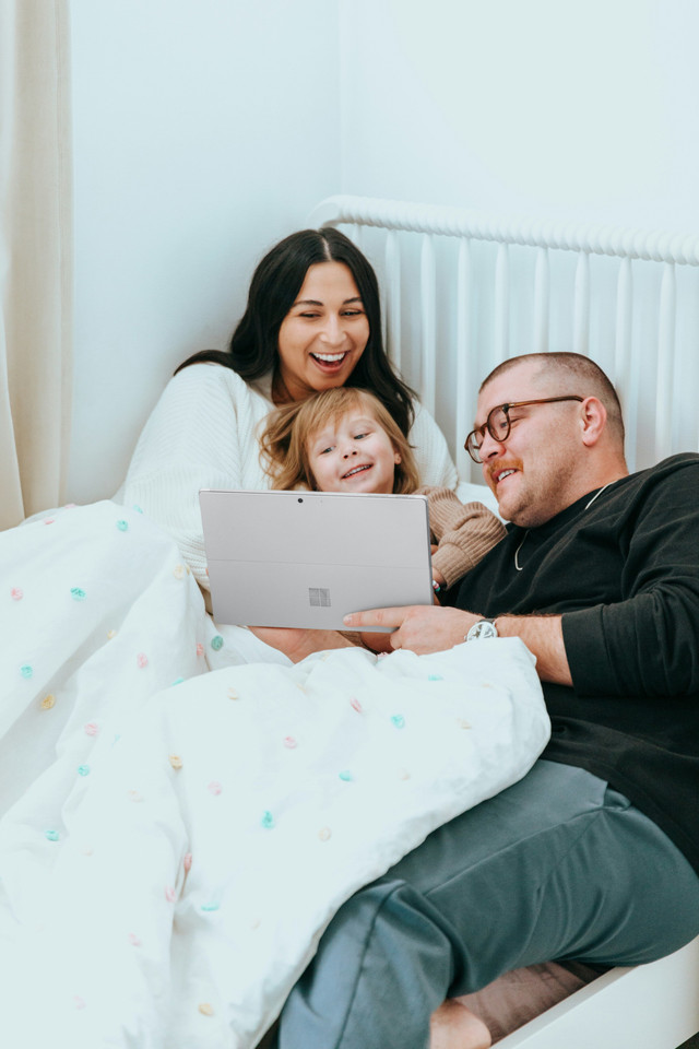 Orangtua dan anak beserta pengenalan teknologi. Sumber: https://unsplash.com/photos/a-man-and-a-woman-sitting-on-a-bed-with-a-laptop-TFH8e9Lmp0s?utm_content=creditShareLink&utm_medium=referral&utm_source=unsplash