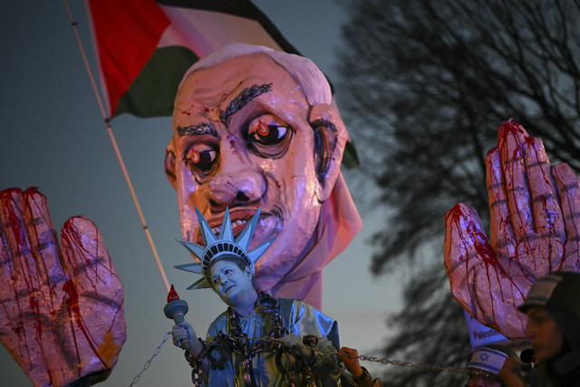 Seorang aktivis berpakaian Patung Liberty ditarik dengan belenggu saat unjuk rasa "Arrest Netanyahu at the White House Rally" mendukung warga Palestina di dekat Gedung Putih, Washington DC, Amerika Serikat, Selasa (4/2/2025). Foto: Mandel Ngan/AFP