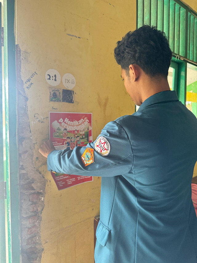 Proses Pemasangan Poster Anti-Bullying di SMP 2 Kandeman