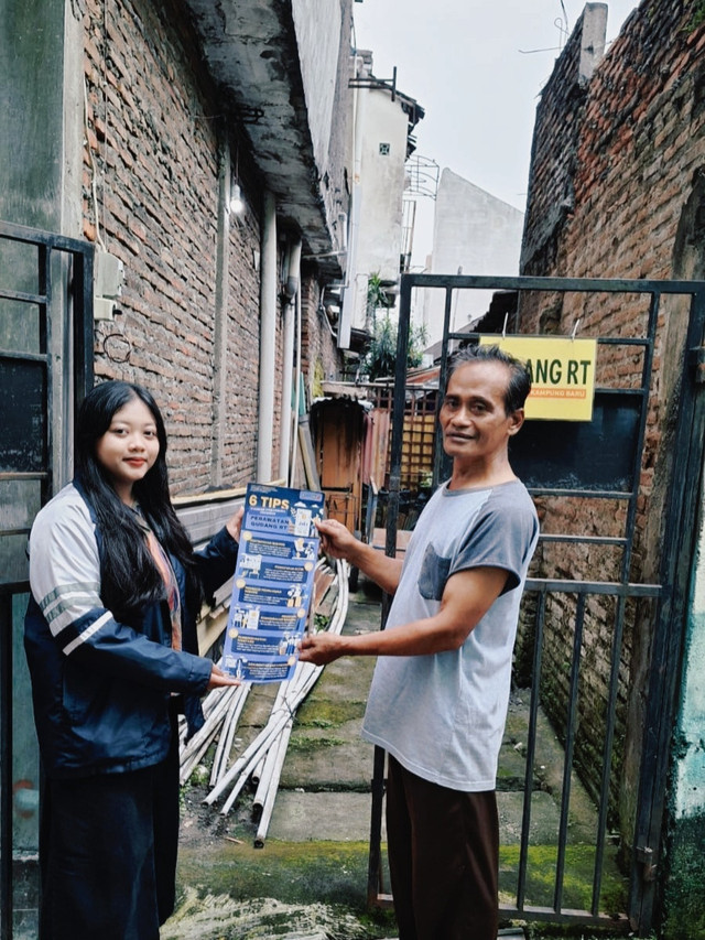 Mahasiswa KKN Tim I UNDIP menyerahkan poster SOP Perawatan Barang kepada pengelola Gudang RT sebagai langkah optimalisasi gudang RT.