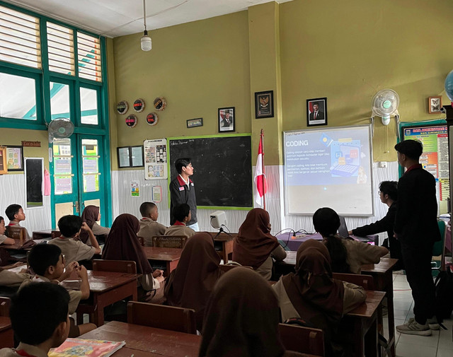 (Gambar: Siswa SDN 01 Girimoyo mengikuti sesi pembelajaran coding interaktif menggunakan platform CodeCombat, didampingi oleh tim PMM Kelompok 58, Sabtu, 1 Februari 2025. Sumber: Dokumentasi PMM Kelompok 58.)