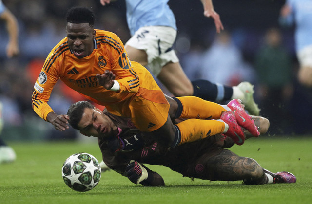 Vinicius Junior dari Real Madrid beraksi dengan Ederson dari Manchester City pada pertandingan Liga Champions leg pertama antara Manchester City vs Real Madrid di Stadion Etihad, Manchester, Inggris, Rabu (12/2/2025) dini hari WIB. Foto: Scott Heppell/REUTERS