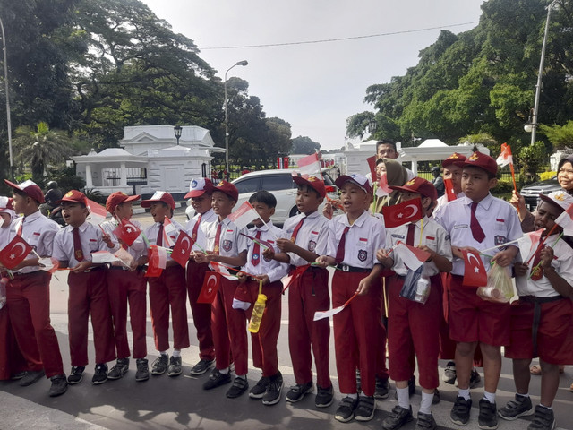 Pelajar dari tingkat SD dan SMP didampingi oleh gurunya menyambut Presiden Turki Erdogan di pintu utama Istana Bogor, Rabu (12/2/2025). Foto: kumparan