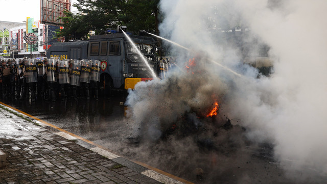 Personel kepolisian memadamkan api menggunakan mobil water cannon saat membubarkan massa yang menghalangi proses eksekusi lahan di Jalan AP Pettarani, Makassar, Sulawesi Selatan, Kamis (13/2/2025). Foto: ANTARA FOTO/Arnas Padda