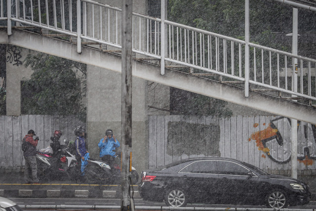 Pengendara motor berteduh di bawah jembatan penyeberangan orang (JPO) saat hujan mengguyur di kawasan Jalan Gatot Subroto, Jakarta, Senin (17/2/2025). Foto: Jamal Ramadhan/kumparan