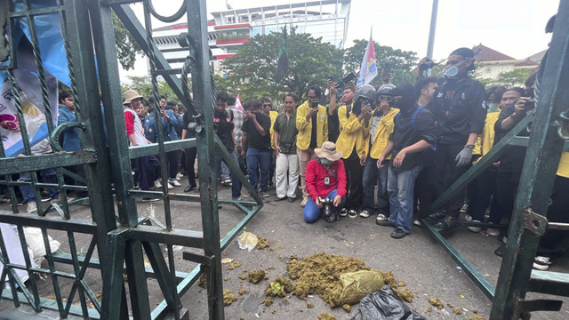 Massa aksi "Semarang Menggugat" membuang kotoran sapi dan air comberan di depan gerbang kantor Gubernur-DPRD Jawa Tengah. Foto: Intan Alliva Khansa/kumparan