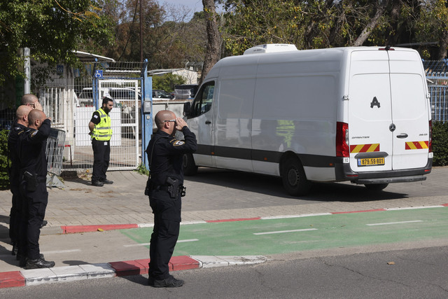 Polisi Israel memberi hormat saat konvoi kendaraan yang mengangkut jenazah empat sandera Israel yang diserahkan oleh Hamas, memasuki Pusat Kedokteran Forensik Nasional di Tel Aviv, Kamis (20/2/2025). Foto: Jack Guez/AFP