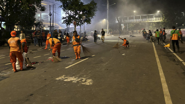 Petugas PPSU mulai membersihkan Jalan Medan Merdeka Barat, Jakpus saat massa aksi bergeser ke bundaran Patung Kuda pada Jumat (21/2/2025). Foto: Abid Raihan/kumparan