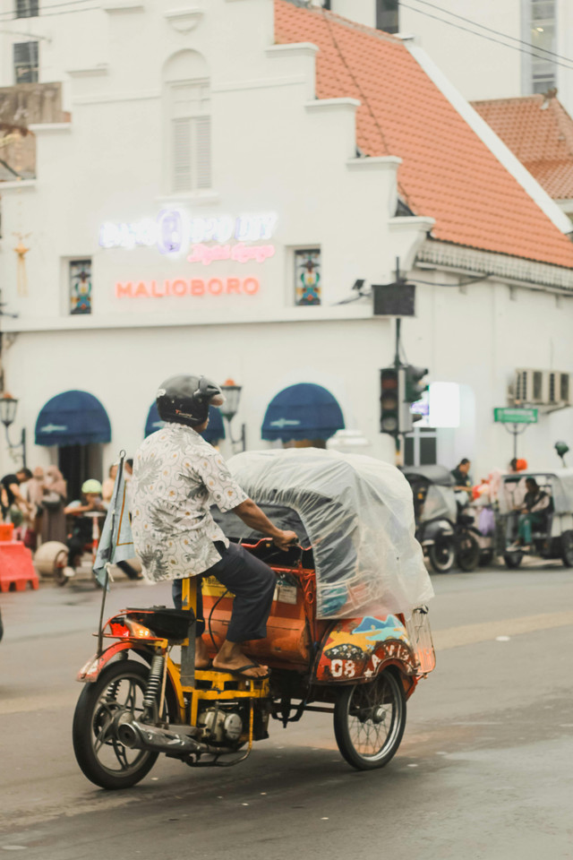 Photo by Bangunfii: https://www.pexels.com/photo/driver-with-helmet-driving-rickshaw-on-street-13957117/