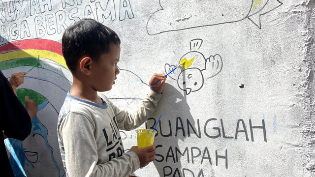 Seorang anak sedang membuat mural tembok di Jalan Merdeka, Gang Belibis Pontianak. Foto: Alycia Tracy Nabila/Hi!Pontianak