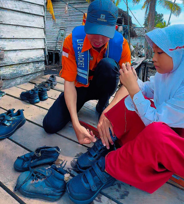 Tim Rumah Zakat Kalbar saat mengenakan sepatu baru ke siswa di Sungai Satu, Batu Ampar. Foto: Dok. Instagram @rumahzakatkalbar