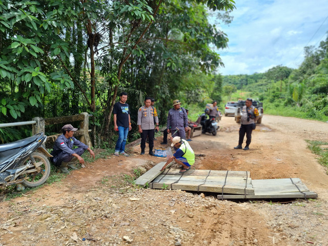 Personel Polsek Tumbang Titi dan warga saat memperbaiki jembatan. Foto: Dok Polres Ketapang