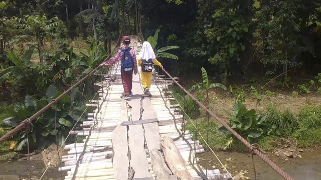 Masyarakat Desa Batulawang, Kecamatan Cibinong, Kabupaten Cianjur, Jawa Barat harus berjuang bertaruh nyawa melintasi jembatan gantung lapuk untuk beraktivitas sehari-hari. Foto: kumparan