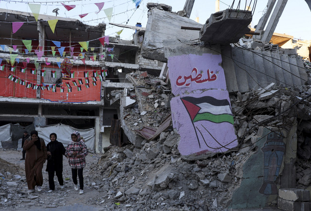 Sejumlah warga melintas dibawah pernak pernik menyambut Ramadan di Khan Younis, Gaza Selatan, Kamis (27/2/2025). Foto: Ramadan Abed/REUTERS