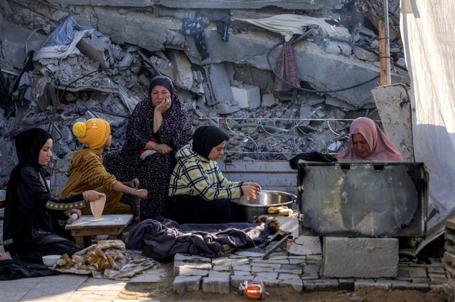 Warga Palestina menyiapkan makanan untuk berbuka puasa di tengah bangunan yang hancur di Jabalia, Jalur Gaza utara, Sabtu (1/3/2025). Foto: Bashar Taleb / AFP