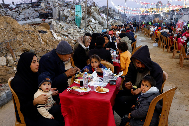 Warga Palestina berbuka puasa bersama di tengah bangunan yang hancur di Jalur Gaza selatan, Sabtu (1/3/2025). Foto: Hatem Khaled/REUTERS