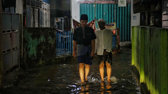 Dua warga yang menerobos genangan air akibat hujan yang terjadi sejak sore hari di wilayah Palembang, Minggu (2/3) Foto: ary/urban id