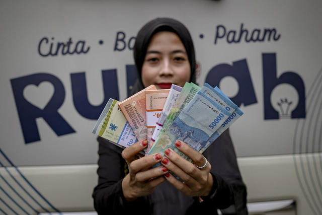 Warga menunjukkan uang pecahan baru saat layanan penukaran uang dari mobil kas keliling Bank Indonesia di Masjid Al Azhar, Jakarta, Selasa (4/3/2025). Foto: Jamal Ramadhan/kumparan