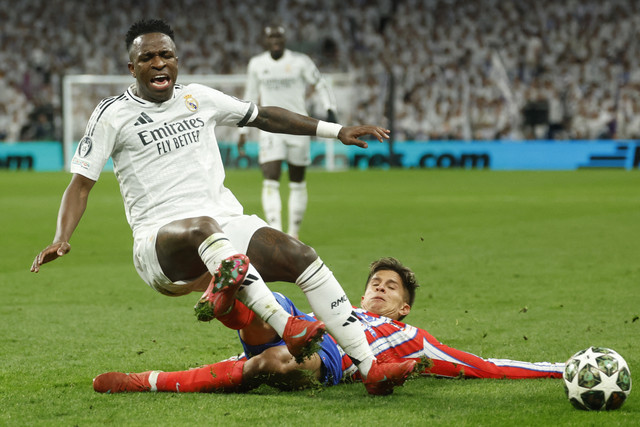 Pemain Real Madrid Vinicius Junior berebut bola dengan pemain Atletico Madrid Giuliano Simeone pada pertandingan Leg Pertama Liga Champions Eropa di Santiago Bernabeu, Madrid, Spanyol, Selasa (4/3/2025). Foto: Pierre-Philippe Marcou/AFP