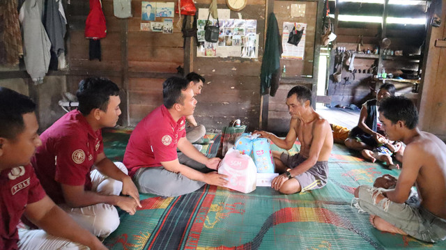 Bripka Aji menyerahkan bantuan untuk anak yatim piatu di Tapang Perodah. Foto: Dok. Humas Polres Sekadau