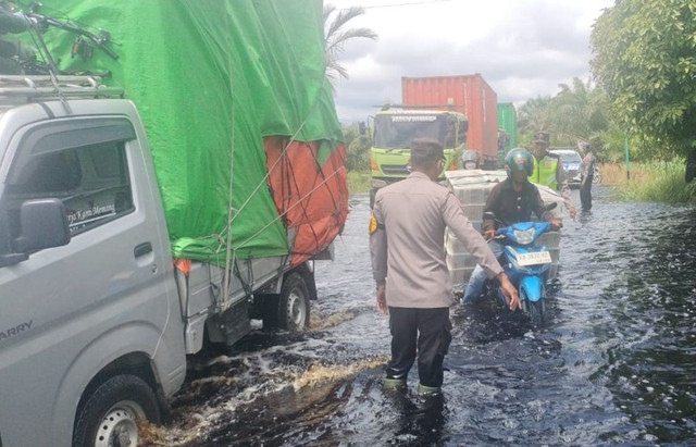 Polisi melakukan pengaturan lalu lintas di Jalan Trans Kalimantan yang terendam banjir. Foto: Dok. Polres Kubu Raya