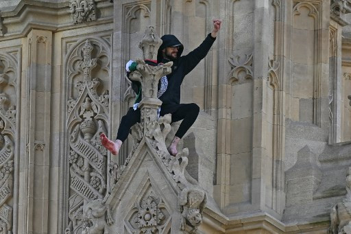 Seorang pria memanjat Big Ben, atau Menara Elizabeth. Ia membawa bendera Palestina, pada Sabtu (8/3). Foto: Ben STANSALL / AFP