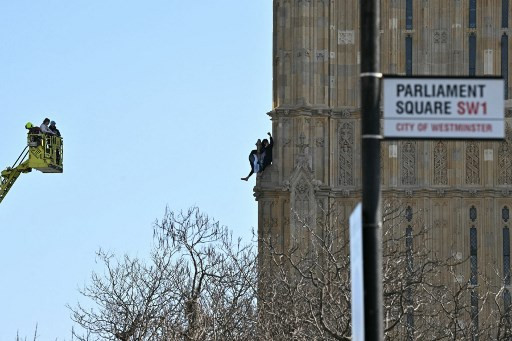 Seorang pria memanjat Big Ben, atau Menara Elizabeth. Ia membawa bendera Palestina, pada Sabtu (8/3). Foto: Ben STANSALL / AFP