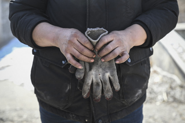 Sarung tangan yang kotor: Seorang distributor batu bara sedang memegang sarung tangannya di Ulan Batar, Mongolia. Foto: Jade Gao/AFP