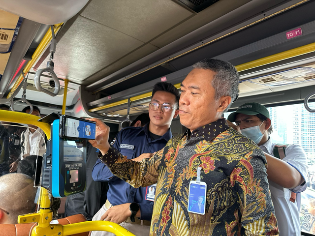 Direktur Retail Funding and Distribution BRI Andrijanto (kanan) saat menggunakan QRIS TAP pada Bus Royal Trans. Foto: Dok. BRI