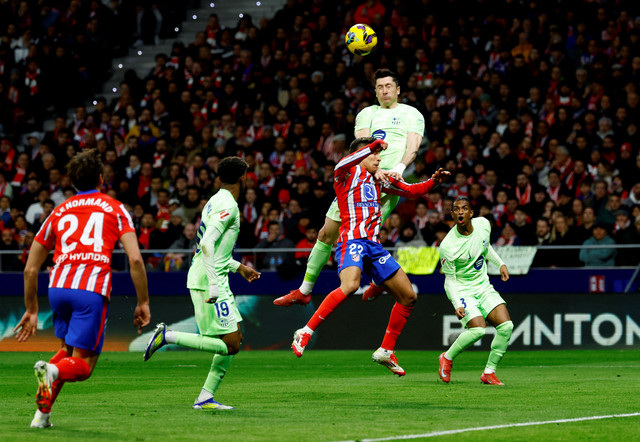 Duel udara Giuliano Simeone dengan Robert Lewandowski saat Atletico Madrid vs Barcelona dalam laga pekan ke-28 Liga Spanyol 2024/25 di Stadion Metropolitano, Senin (17/3) dini hari WIB. Foto: REUTERS/Susana Vera