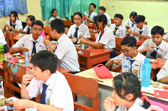 Sejumlah siswa menyantap menu makanan bergizi gratis (MBG) yang dibagikan di SMP Negeri 1 Denpasar, Bali, Senin (17/3/2025). Foto: Fikri Yusuf/ANTARA FOTO