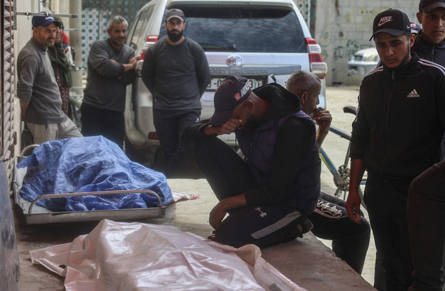 Kerabat berduka di dekat jenazah tiga pria Palestina yang terbunuh dalam serangan pesawat tak berawak Israel di sebelah timur kamp Bureij, di rumah sakit Syuhada al-Aqsa di Deir el-Balah di Jalur Gaza tengah, Senin (17/3/2025). Foto: EYAD BABA/AFP