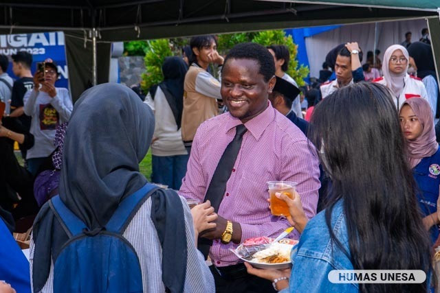 Mahasiswa Program BIPA asal Uganda, Denis Angella berinteraksi (sekaligus belajar bahasa Indonesia) dengan mahasiswa dan warga sekitar sembari membagikan menu buka bersama.