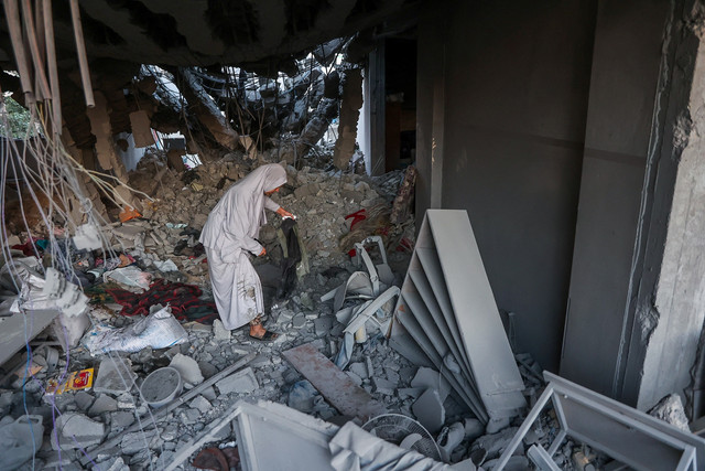 Warga Palestina melihat kondisi reruntuhan sekolah yang menjadi kamp pengungsian setelah serangan Israel di Kota Gaza, Selasa (18/3/2025). Foto: Omar AL-QATTAA / AFP