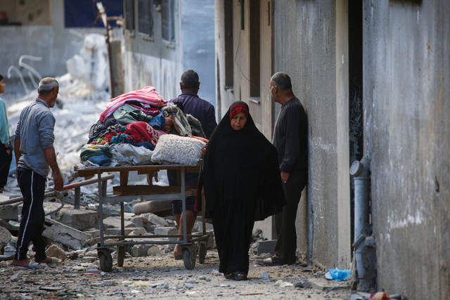 Warga Palestina membawa barang-barang yang diselamatkan dari puing-puing rumahnya yang hancur akibat serangan Israel di kamp pengungsi Nuseirat, Jalur Gaza bagian tengah, Selasa (18/3/2025). Foto: Eyad BABA / AFP