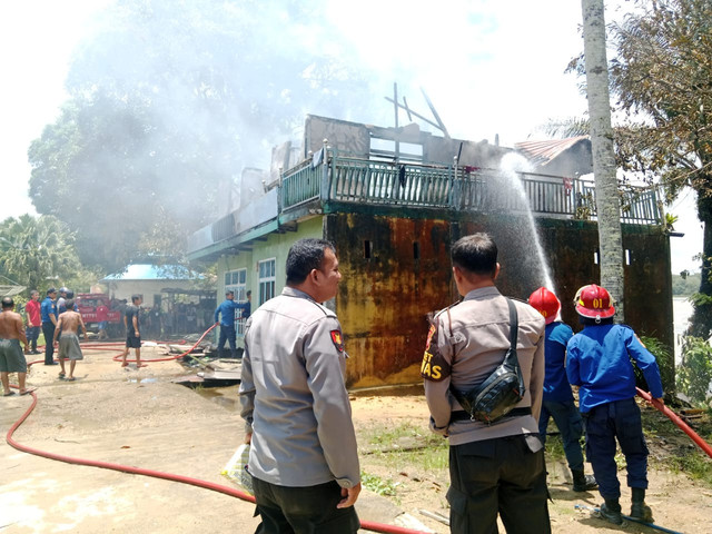 Petugas memadamkan api yang menghanguskan rumah warga di Merapi. Foto: Dok. Polres Sekadau