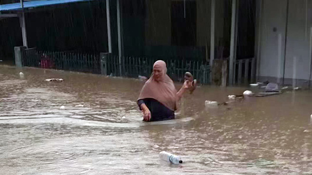 Seorang warga di Kelurahan Banjer, Kota Manado, Sulawesi Utara, berjalan di tengah banjir, Jumat, 21 Maret 2025.