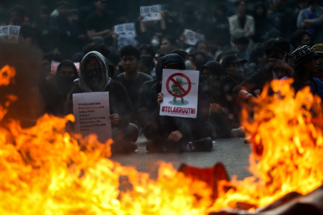 Warga membentangkan poster saat unjuk rasa menolak revisi Rancangan Undang-Undang TNI di depan Gedung DPRD Jawa Barat, Bandung, Indonesia, pada 21 Maret 2025. Foto: Ryan Suherlan/NurPhoto