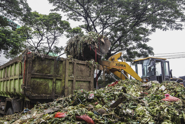 Pekerja mengoperasikan alat berat untuk memindahkan sampah sisa makanan dan sayur ke truk di Pasar Kramat Jati, Jakarta Timur. Foto: Darryl Ramadhan/kumparan