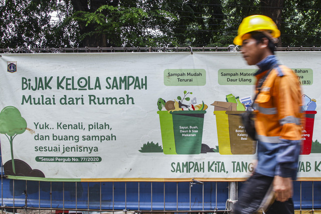 Spanduk informasi: Seorang pekerja melintas dengan latar belakang spanduk bertuliskan "Bijak Kelola Sampah Mulai dari Rumah" di Jalan Raya Kalimalang, Jakarta. Foto: Darryl Ramadhan/kumparan