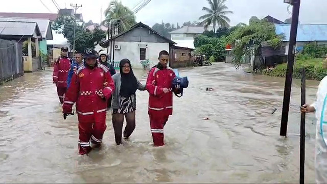 Petugas SAR Ditpolairud Polda Sulawesi Utara, melakukan evakuasi seorang warga yang terjebak banjir di salah satu kelurahan yang ada di Kota Manado, Sabtu (22/3).