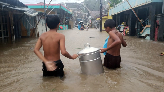 Warga di Kelurahan Mahawu, Kota Manado, mencoba untuk menyelamatkan barang milik mereka dari banjir yang menerjang sejak Jumat (23/3).