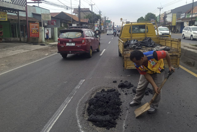 Pekerja memperbaiki jalan yang berlubang di Karawang, Jawa Barat, Selasa (25/3/2025). Foto: Dok. kumparan