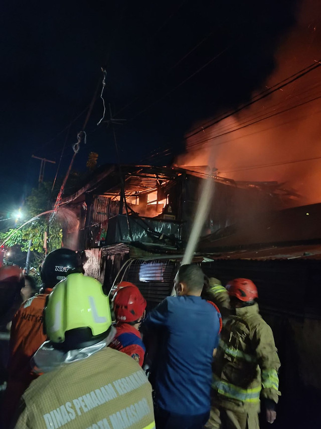Petugas berusaha memadamkan api yang membakar permukiman padat di Makassar, satu orang tewas, Minggu (6/4) dini hari. Foto: Dok kumparan