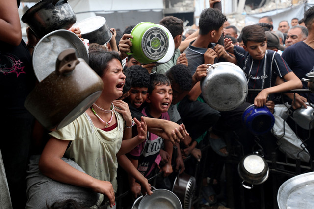 Warga Palestina berkumpul untuk menerima makanan yang dimasak oleh dapur amal di Beit Lahia, Jalur Gaza utara, Kamis (24/4/2025). Foto: Mahmoud Issa/REUTERS