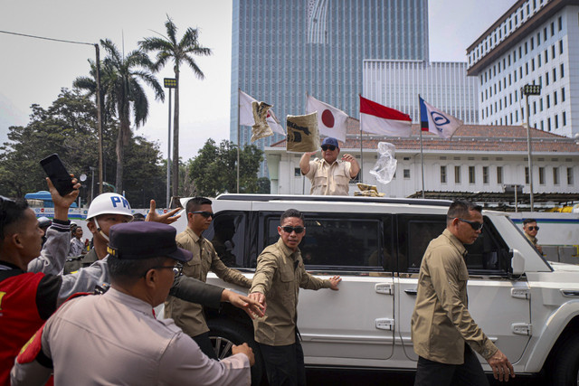 Presiden Republik Indonesia Prabowo Subianto membagikan kaos dari Mobil Maung saat meninggalkan perayaan May Day di kawasan Monas, Jakarta, Kamis (1/5/2025). Foto: Iqbal Firdaus/kumparan
